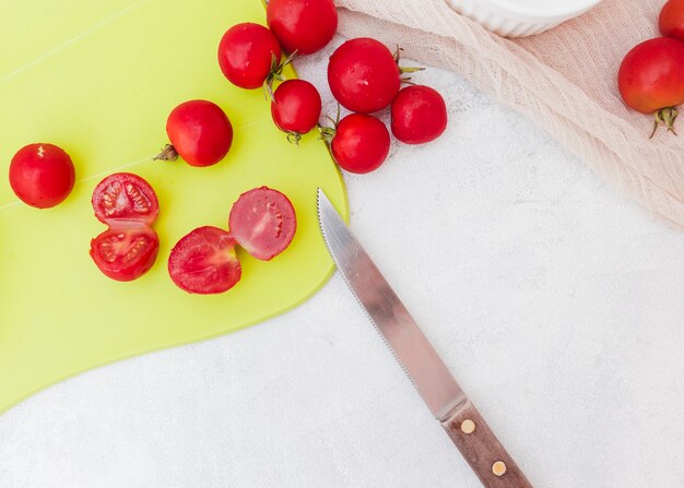 Slices of tomatoes on chopping board with sharp knife