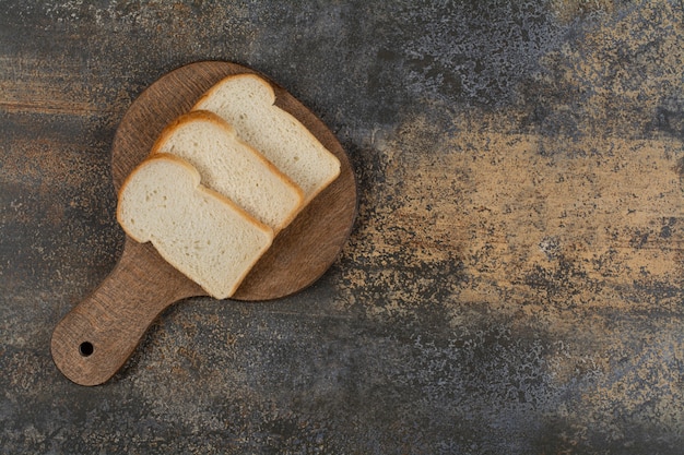 Free Photo slices of white toast bread on wooden cutting board.