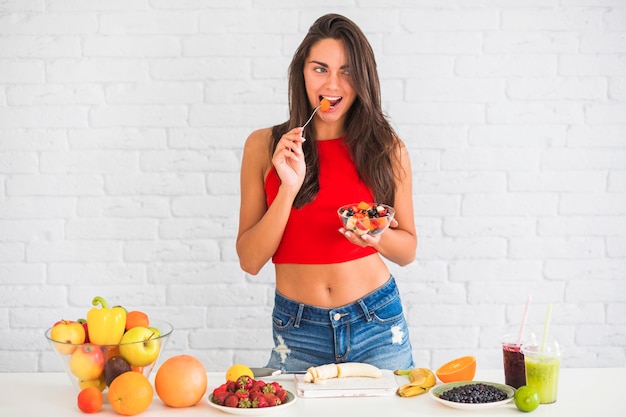 Slim attractive young woman eating fresh fruit salad