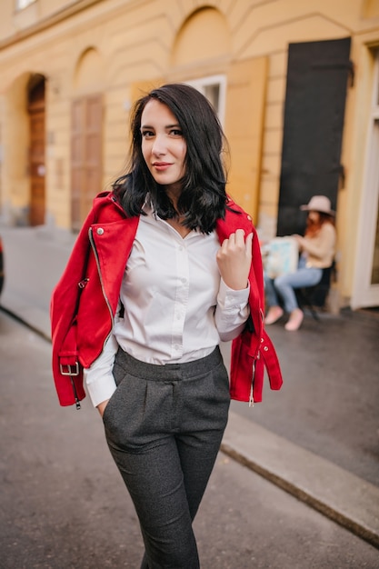 Free Photo slim brunette lady in gray pants posing with gently smile on the street