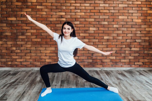 Slim  brunette  woman practices yoga in white backlit studio.