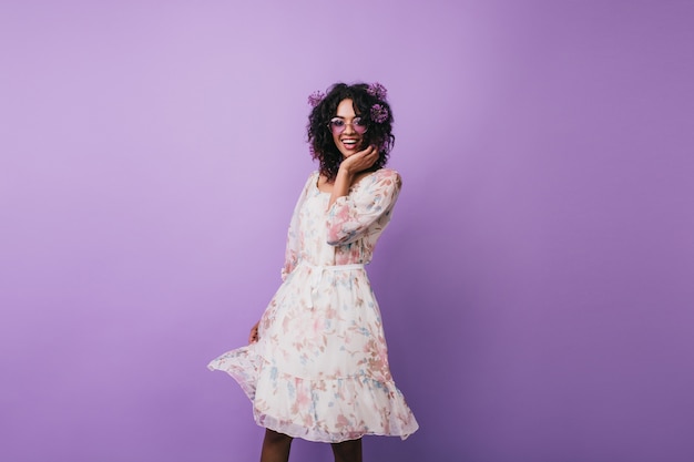 Slim girl with alliums in hair happy dancing. Pleasant african young woman in vintage dress posing.