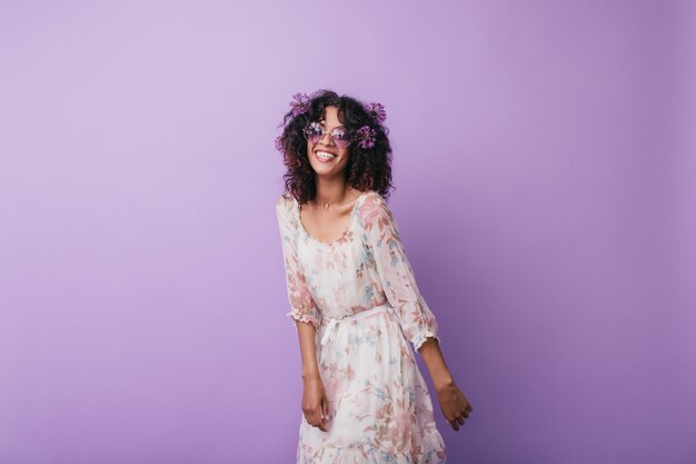 Slim inspired african girl laughing. Indoor photo of enthusiastic curly young woman posing with alliums in hair.