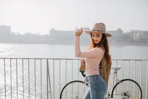 Free photo slim smiling woman in jeans and pink shirt posing with bicycle