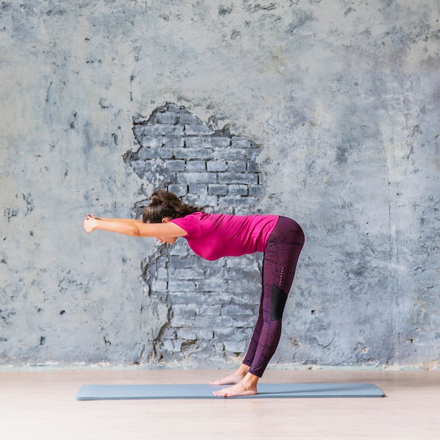 Free photo slim woman doing fitness exercise against weathered grey wall