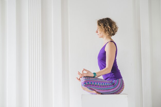 Slim woman in lotus pose on cube