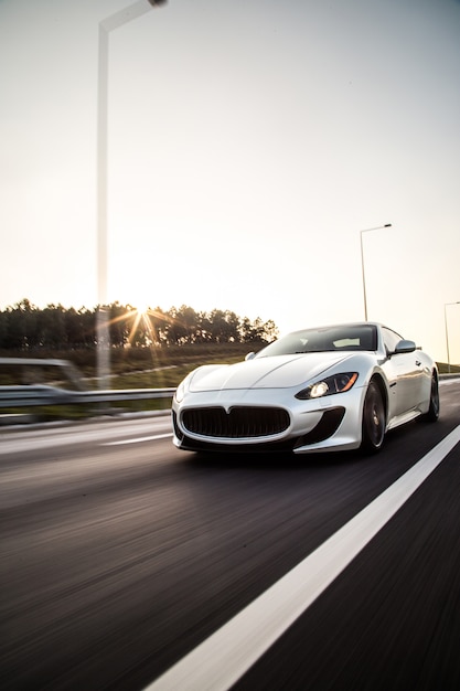 A sliver metallic color sport car driving with high speed on the road.