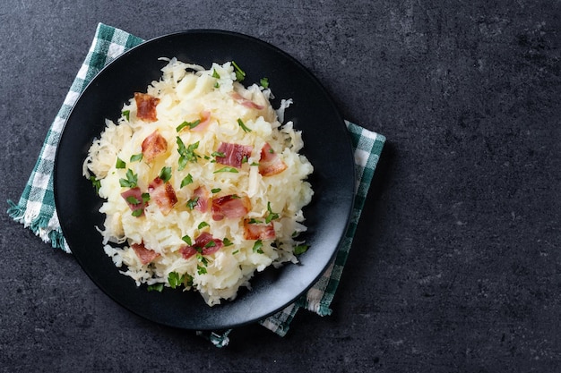 Free Photo slovak potato dumplings halusky with steamed sauerkraut and bacon on black background