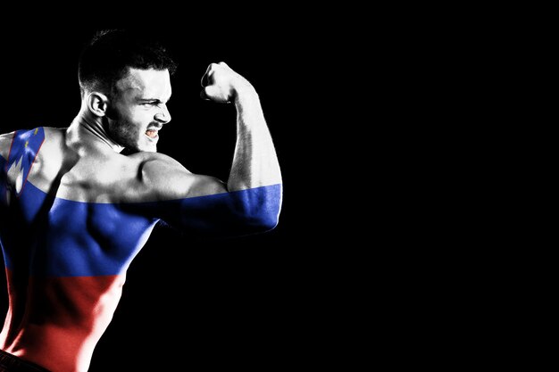 Slovenia flag on handsome young muscular man black background