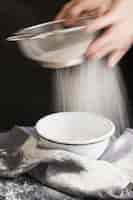 Free photo slow motion shot of aged female hands sifting flour by sieve in bowl