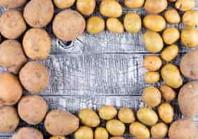 Free photo small and big potatoes on a dark wooden table