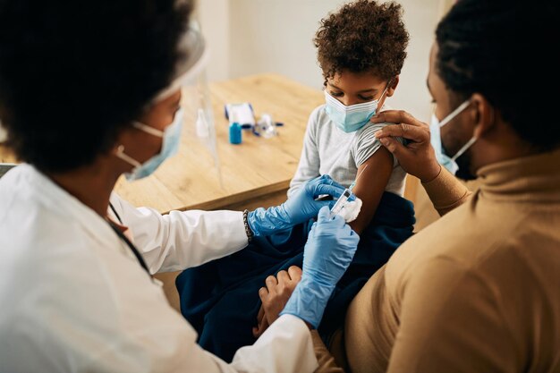 Small black boy receiving vaccine due to COVID19 pandemic