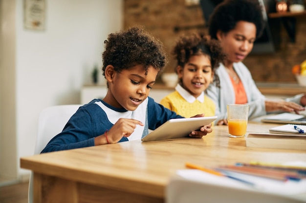 Small black boy surfing the net on digital tablet at home