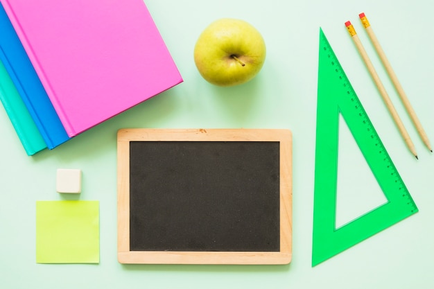 Free Photo small blackboard with stationary and apple 