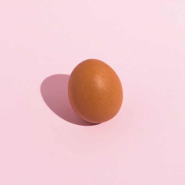 Free photo small brown chicken egg on pink table