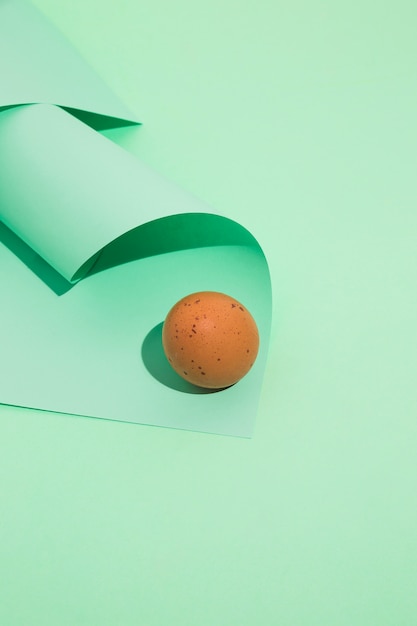 Small brown chicken egg with rolled paper on green table