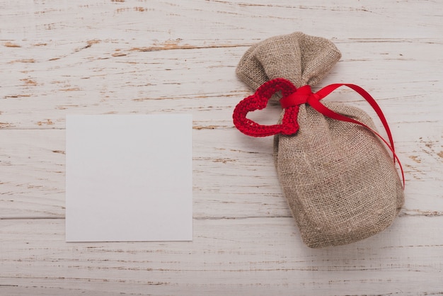 Free photo small brown sack with a red bow and a blank paper