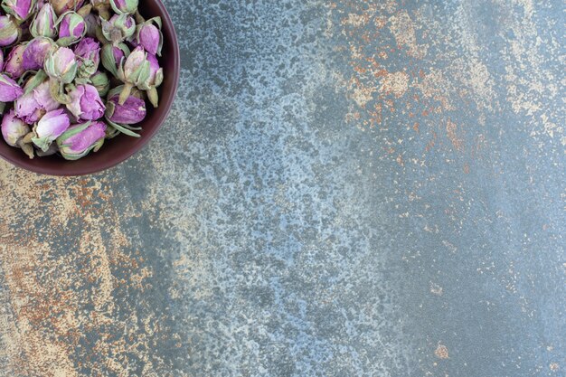 Small budding roses in dark bowl.