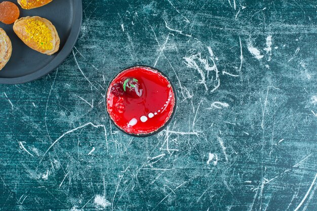 Free Photo small cake next to a bundle of buns on a serving pan on blue.