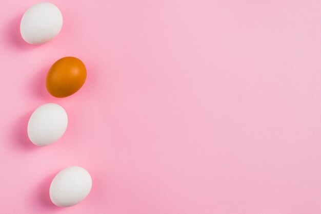 Small chicken eggs scattered on pink table