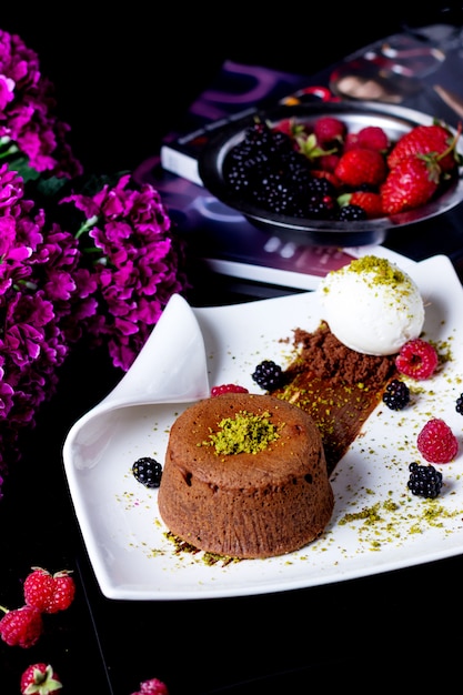 Small chocolate cake garnished with pistachio served with vanilla ice cream