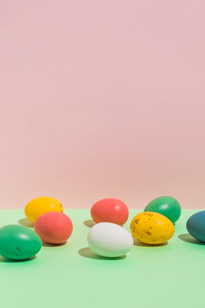 Free photo small colorful easter eggs scattered on bright table