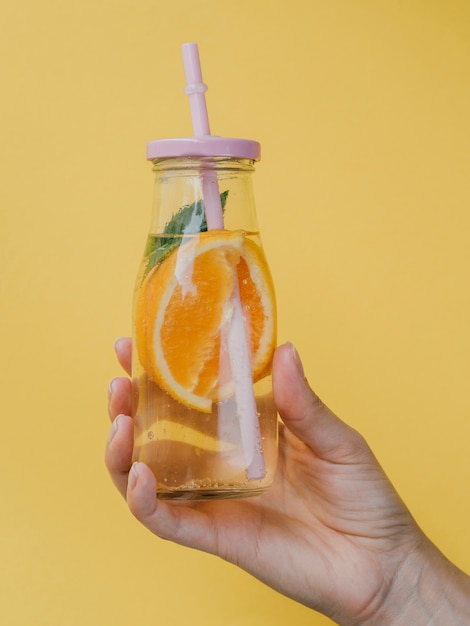 Small container for natural juice with straw held in hand