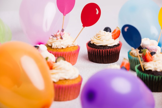 Free photo small cupcakes with air balloons on light table