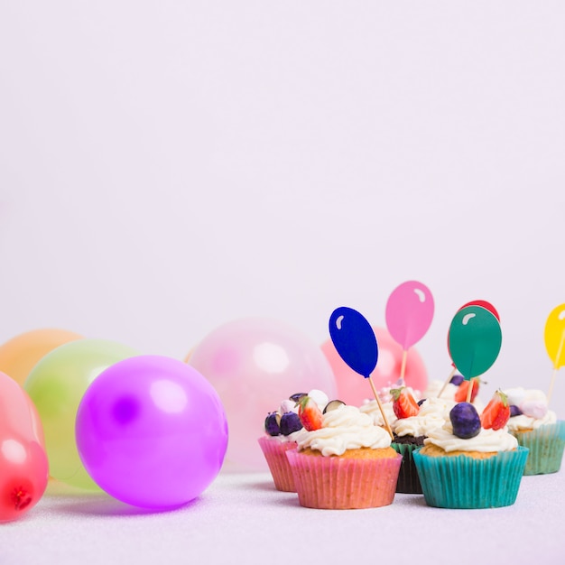 Free photo small cupcakes with air balloons on white table