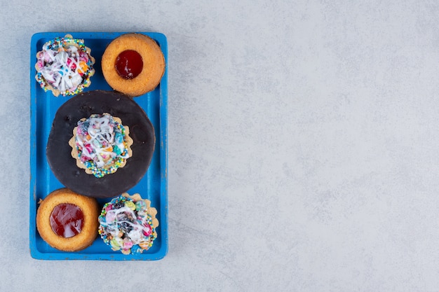 Small dessert assortment on a blue platter on marble table.