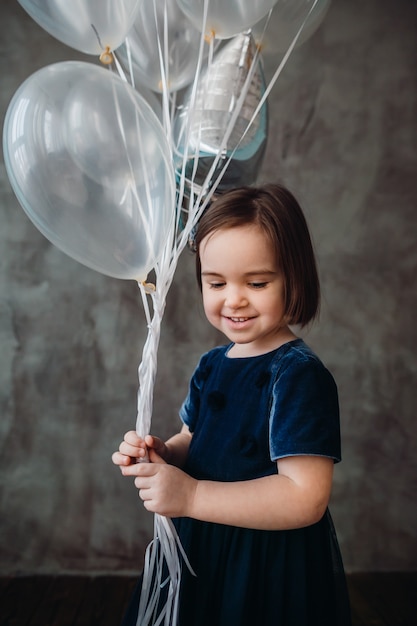 The small girl keeps ballons in the room