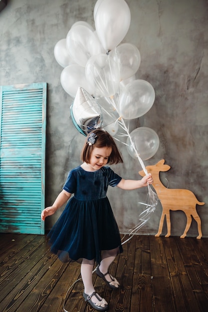 Free photo the small girl keeps ballons in the room