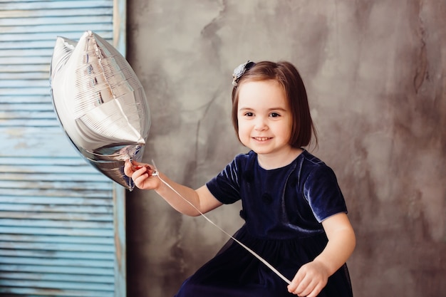 The small girl keeps star and sits  on the ladder