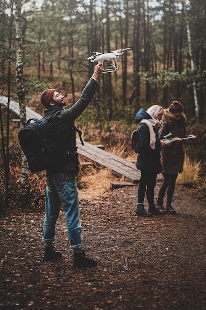 Free photo small group of people are enjoying their hike in autumn forestal park, one of them ia making photo via drone.