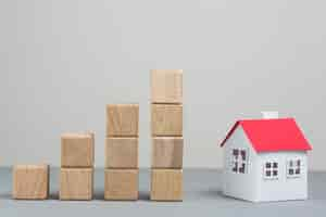 Free photo small house model and stack of increasing wooden block on grey backdrop