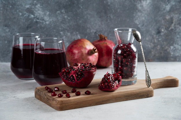 A small jar full of pomegranate and cups of juice.