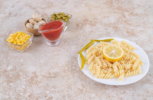 Small ketchup container and salad ingredients next to main course displayed on marble surface.