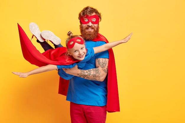 Free photo small kid plays superhero, being on fathers hands, pretends flying