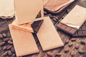 Free photo small paper bag over the packed chocolate bar with cocoa beans on table