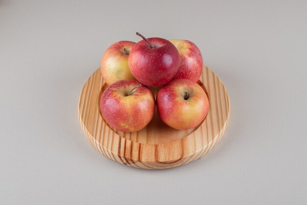 Small pile of apples on a wooden platter on marble 