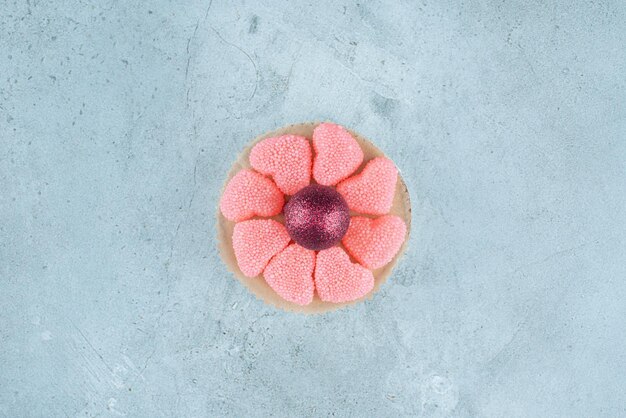 Small platter of marmelades around a decorative ball on marble.