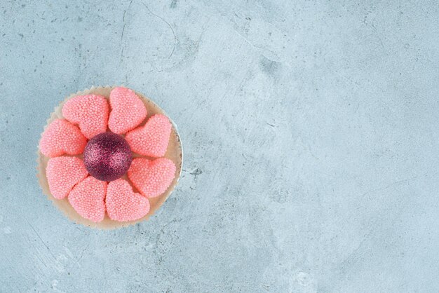 Small platter of marmelades around a decorative ball on marble.