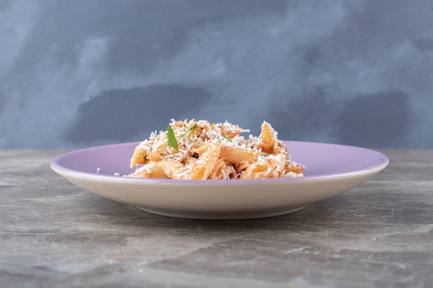 A small portion penne pasta , on the marble surface.