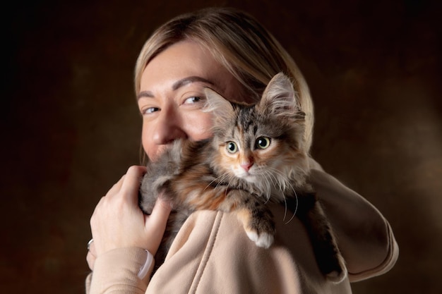 Free photo a small purebred kitten sitting on the shoulder of a young woman