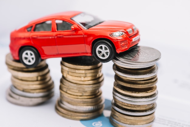 Small red car over the stack of increasing coins