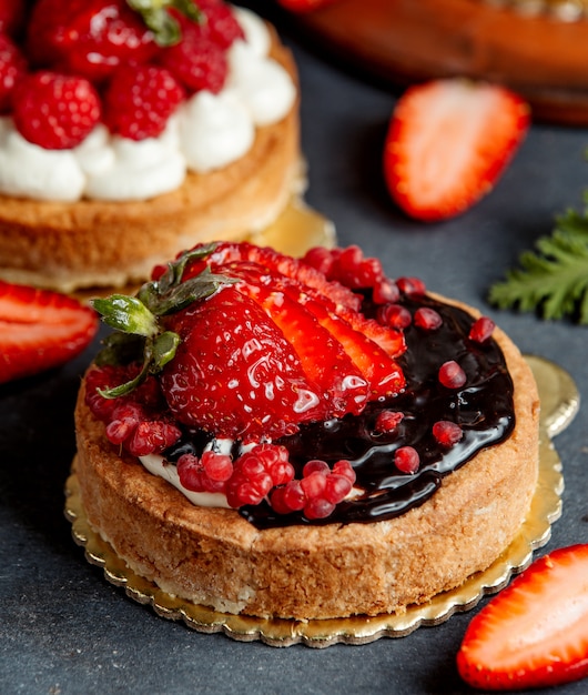 Small round pie decorated with chocolate cream and strawberries