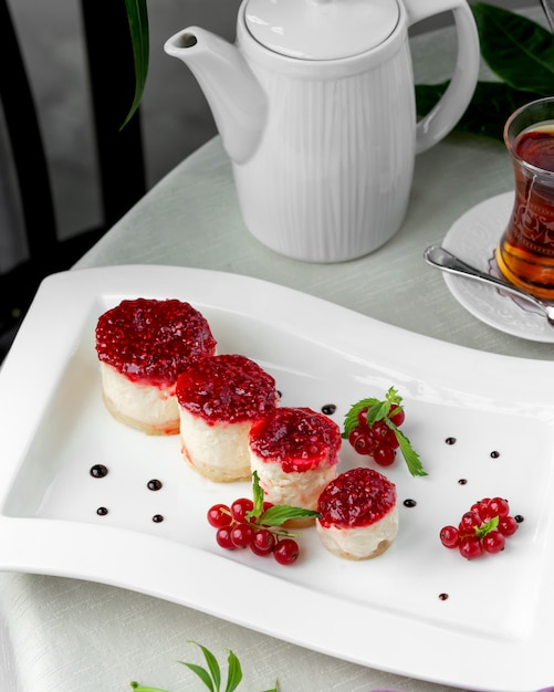 Free Photo small and round red currant cheesecakes plate