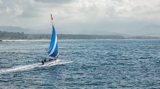 Free Photo small sailboat floats on water with amazing mountain views. 