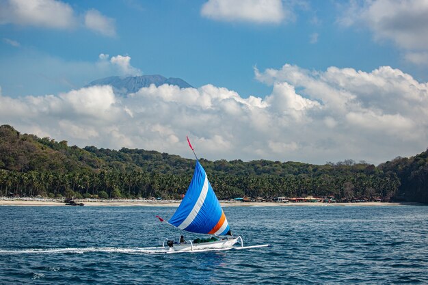 Small sailboat floats on water with amazing mountain views. 