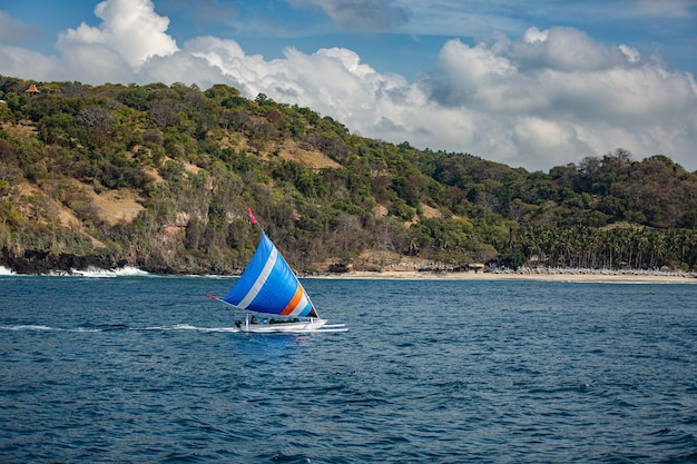 Small sailboat floats on water with amazing mountain views. 